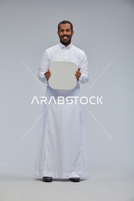 رجل سعودي بالثوب يحمل لوحة بيضاء فارغة مستديرة