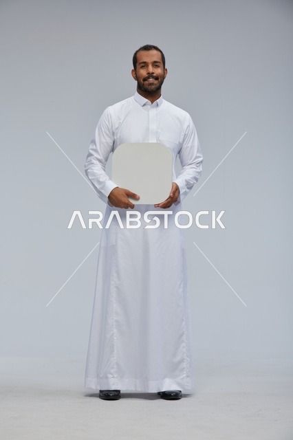 رجل سعودي يحمل لوحة بيضاء فارغة في الاستديو