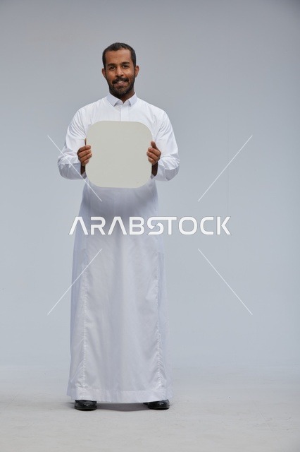 رجل سعودي يحمل لوحة بيضاء فارغة في الاستوديو