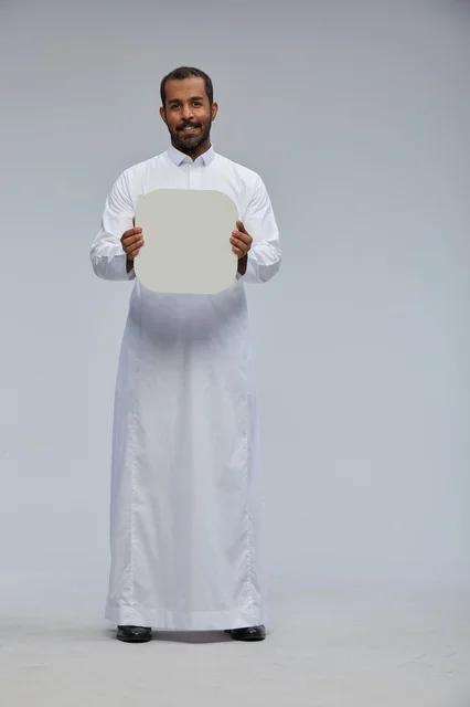 رجل سعودي يحمل لوحة بيضاء فارغة في الاستوديو