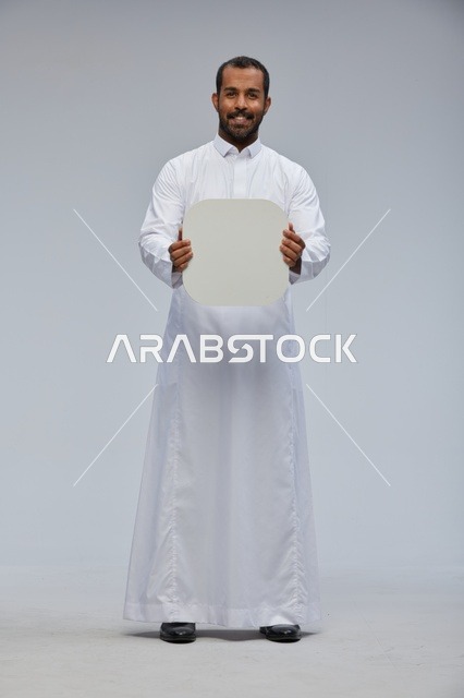 رجل سعودي يحمل لوحة بيضاء فارغة في استوديو احترافي