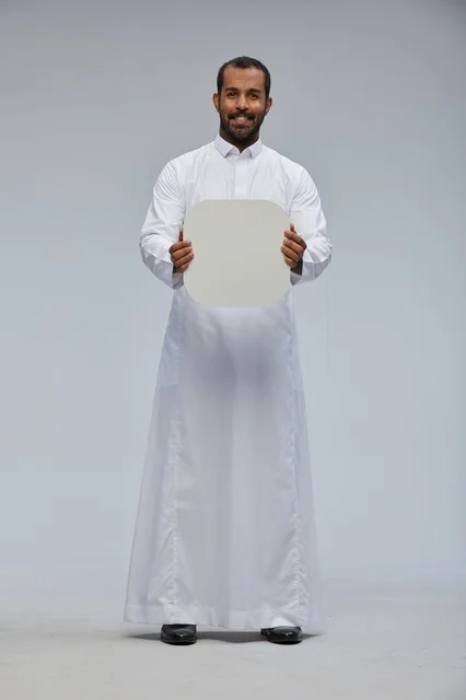 رجل سعودي يحمل لوحة بيضاء فارغة في استوديو احترافي