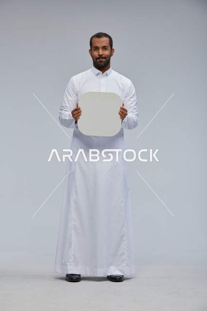 رجل سعودي بالثوب التقليدي يحمل لوحة بيضاء فارغة