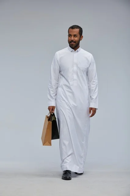 رجل سعودي بالثوب الأبيض يحمل أكياس تسوق