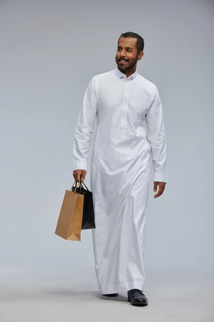 رجل سعودي بالثوب الأبيض يحمل أكياس تسوق في الاستوديو