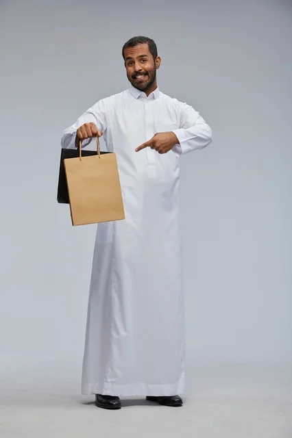 رجل سعودي بالثوب التقليدي يحمل أكياس تسوق
