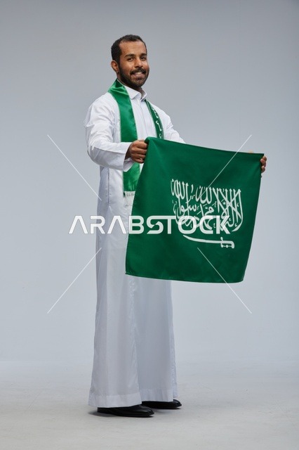 رجل سعودي يحمل العلم الوطني في استوديو تصوير
