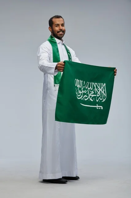 رجل سعودي يحمل العلم الوطني في استوديو تصوير