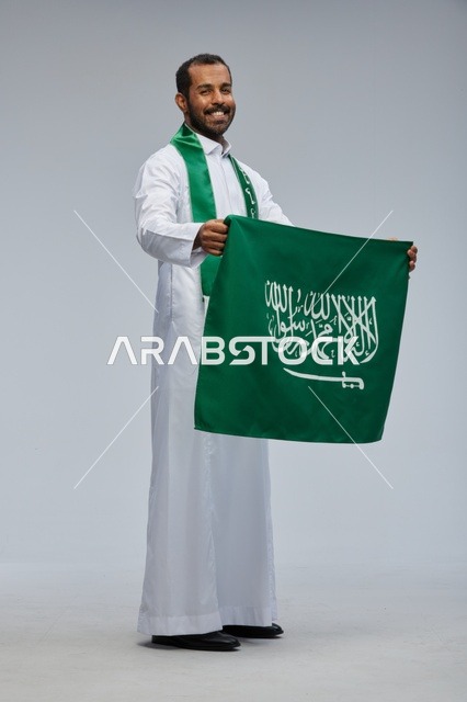Saudi Man Holding National Flag in Studio Portrait