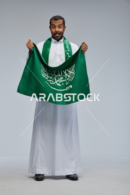 رجل سعودي يحمل العلم الوطني السعودي في الاستوديو