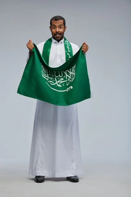 رجل سعودي يحمل العلم الوطني السعودي في الاستوديو