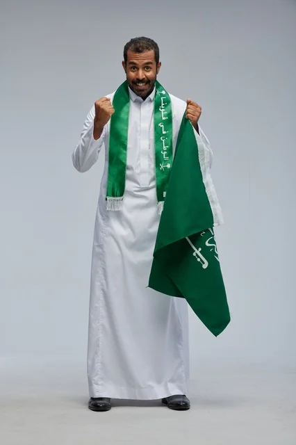 رجل سعودي يحمل العلم الوطني السعودي في احتفال اليوم الوطني