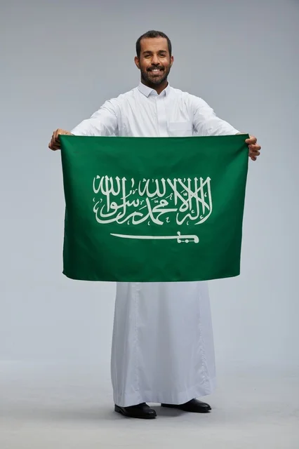 رجل سعودي يحمل العلم الوطني السعودي في الاستوديو