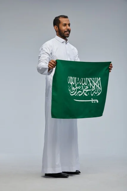 رجل سعودي يحمل العلم الوطني السعودي في تصوير استوديو