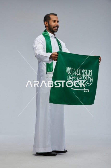 Saudi Man Holding Saudi National Flag in Studio Setting