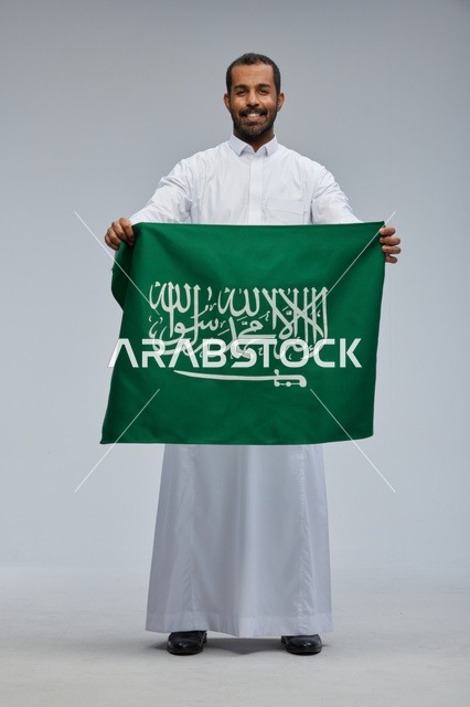 رجل سعودي يحمل العلم الوطني السعودي في استوديو