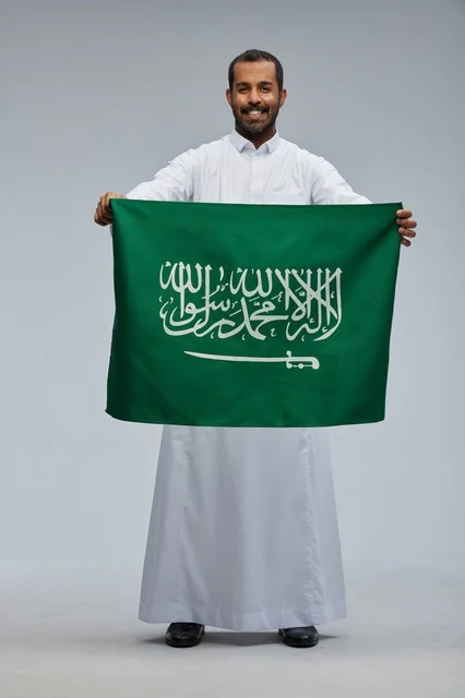 رجل سعودي يحمل العلم الوطني بالثوب التقليدي