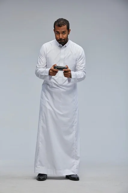 Saudi Man in Traditional Thobe Playing Video Games