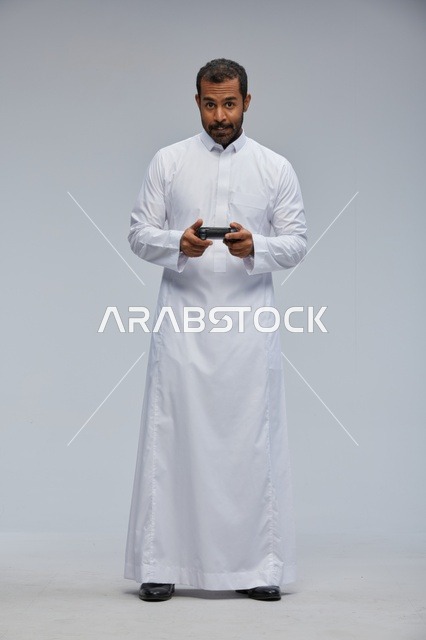 Saudi Man in Traditional Thobe Holding Game Controller