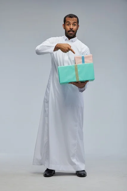 رجل سعودي بالثوب التقليدي يحمل صناديق هدايا مغلفة
