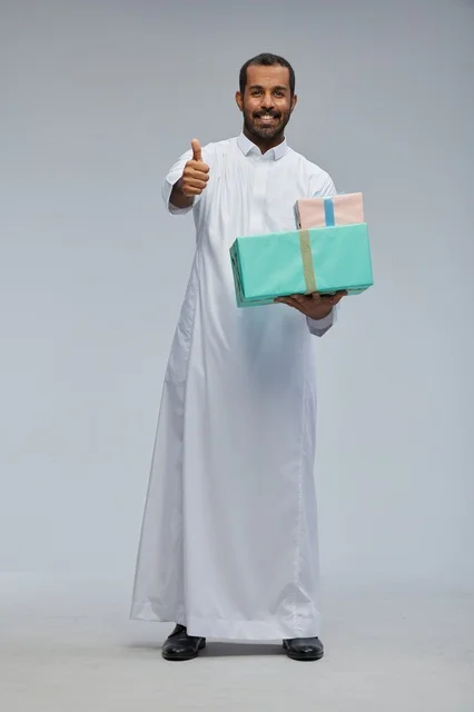 رجل سعودي يحمل صناديق هدايا مع إشارة الإبهام