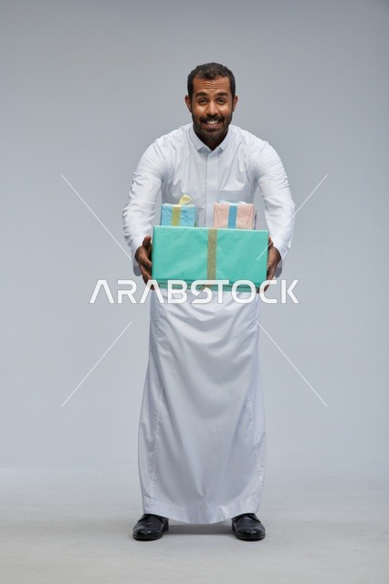 رجل سعودي يحمل صناديق هدايا مغلفة بالثوب التقليدي