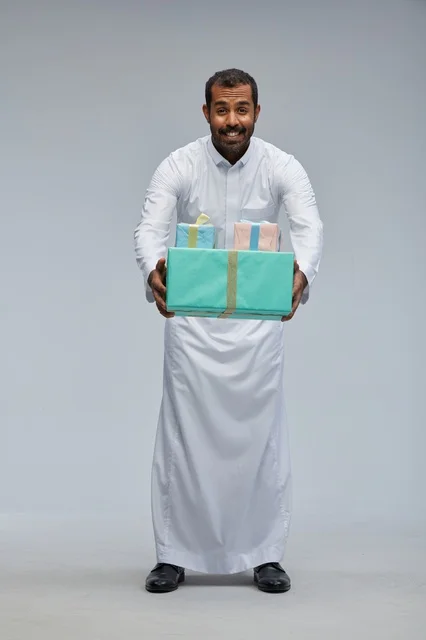 رجل سعودي يحمل صناديق هدايا مغلفة بالثوب التقليدي