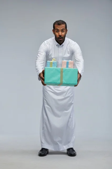 رجل سعودي يحمل صناديق هدايا بتعبير مندهش