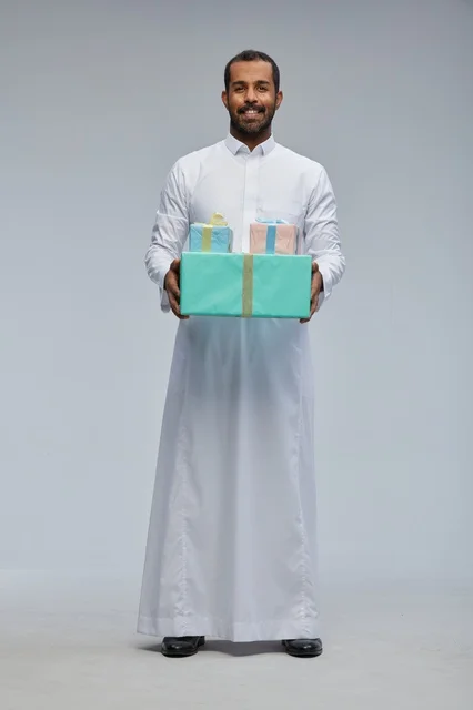 رجل سعودي بالزي التقليدي يحمل صناديق هدايا