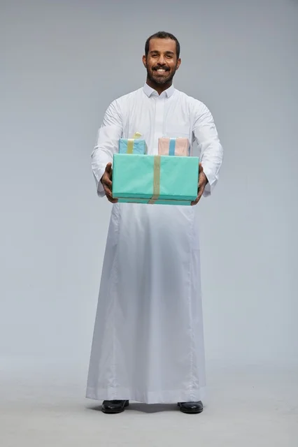 رجل سعودي بالزي التقليدي يحمل صناديق هدايا ملونة