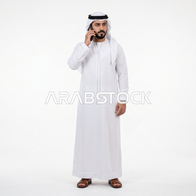 رجل خليجي بالثوب يتحدث بالهاتف على خلفية بيضاء