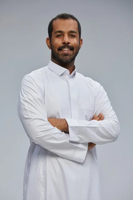 Smiling Saudi Man in White Thobe with Crossed Arms