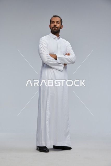 رجل سعودي بالثوب الأبيض مكتوف الذراعين في الاستوديو