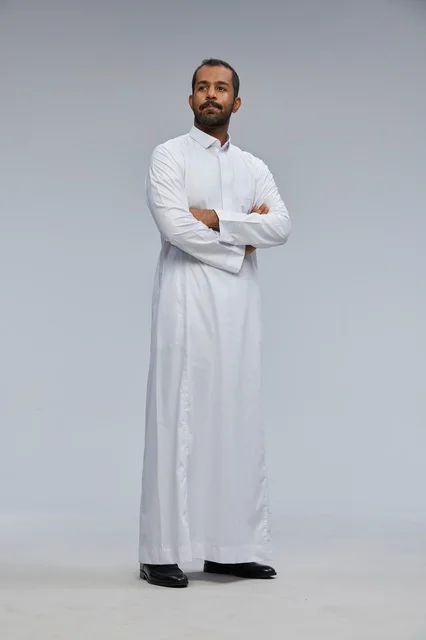 رجل سعودي بالثوب الأبيض مكتوف الذراعين في الاستوديو