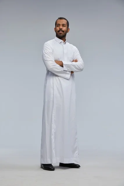 رجل سعودي بالثوب الأبيض مكتوف الذراعين في الاستوديو