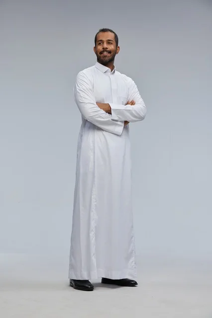 رجل سعودي يقف مكتوف الذراعين بالثوب الأبيض