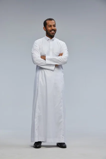 رجل سعودي بالثوب الأبيض مكتوف الذراعين في استوديو