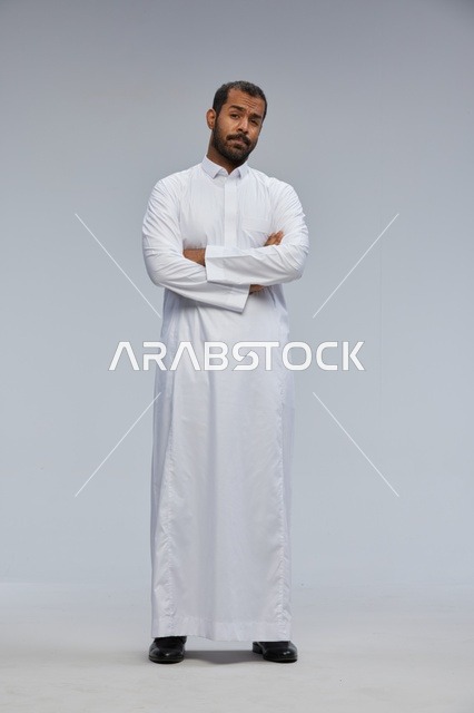 رجل سعودي يرتدي الثوب الأبيض يقف في استوديو تصوير