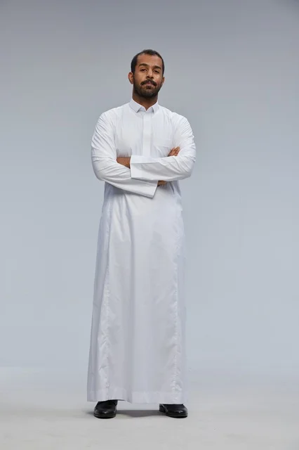 رجل سعودي بالثوب الأبيض يقف بوضعية مكتوفة الذراعين