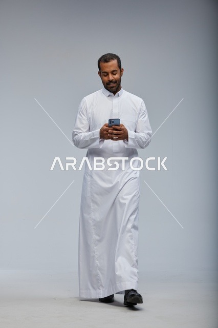 Saudi Man in White Thobe Using Smartphone Studio