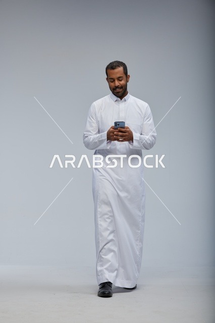 Saudi Man in White Thobe Using Smartphone Studio Shot