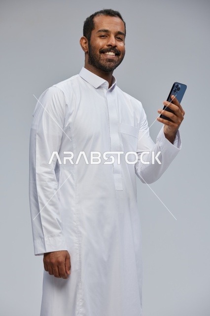 Saudi Man in White Thobe Using Smartphone in Studio