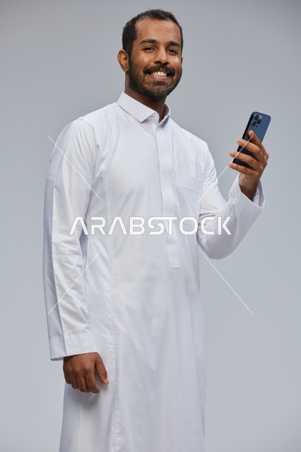 Saudi Man in White Thobe Holding Smartphone Studio