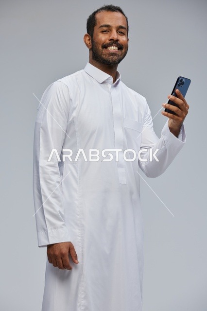Saudi Man in Thobe Using Smartphone Studio Portrait