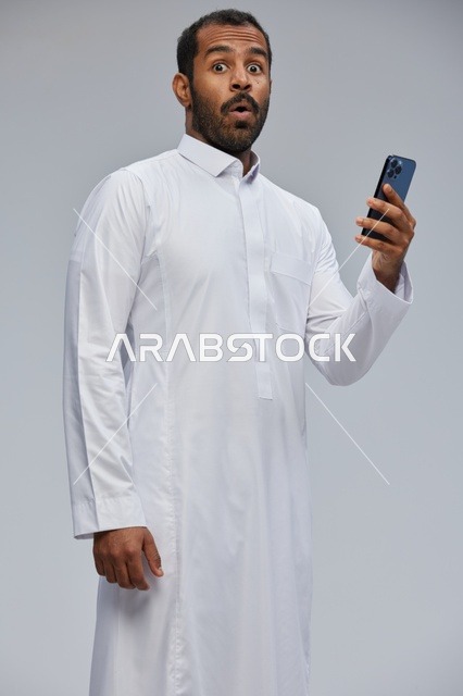 Surprised Saudi Man Using Smartphone in White Thobe