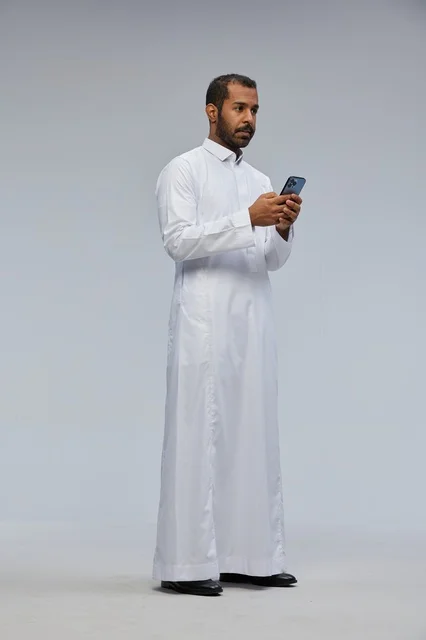 Saudi Man in White Thobe Using Smartphone in Studio