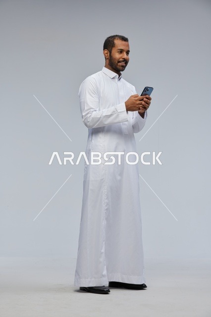 Saudi Man in White Thobe Using Smartphone in Studio