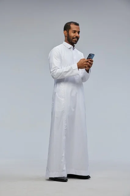 Saudi Man in White Thobe Using Smartphone in Studio
