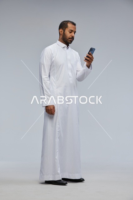 Saudi Man in White Thobe Using Smartphone in Studio