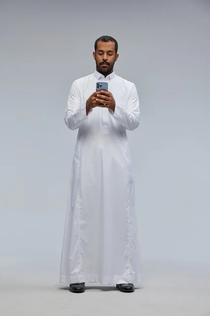 Saudi Man in White Thobe Using Smartphone